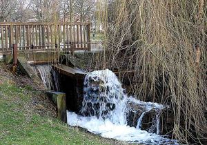 Kleine Holzbrücke und Wassermühle am Tag