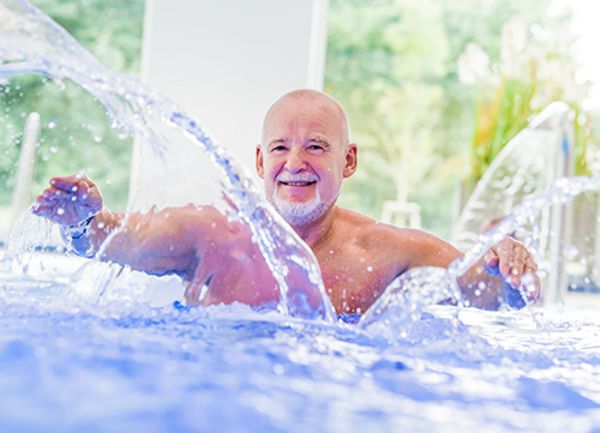 Mensch im Wasser Ein Mann steht in einem Schwimmbecken und wirbelt Wasser mit den Händen auf