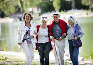 Drei Frauen und ein Mann gehen bei schönem Wetter im Park spazieren