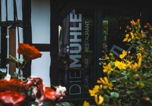 Eingangsbereich der Mühle Bad Laer mit Fachwerk und Blumen