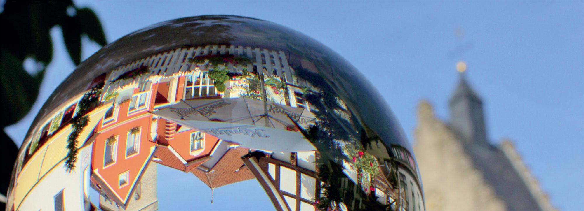 Häuser auf einer Glaskugel als Spiegelbild zu sehen