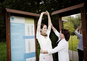 Eine Frau wird von einer anderen Frau bei einer Fitnessübung unterstützt