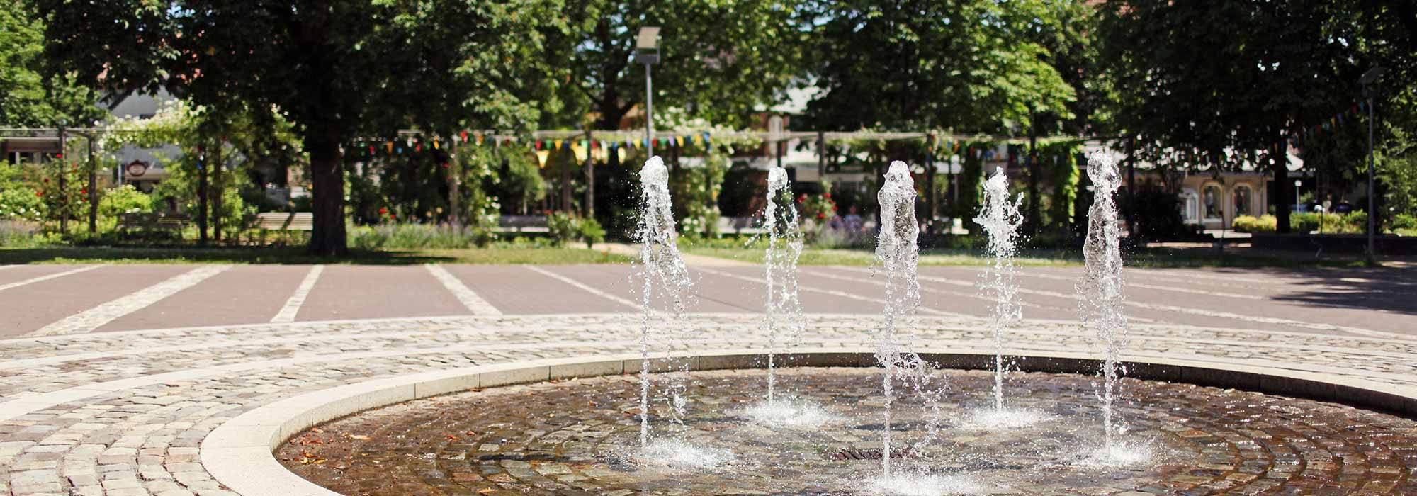 Springbrunnen auf einem Platz im Ort bei sommerlichem Wetter