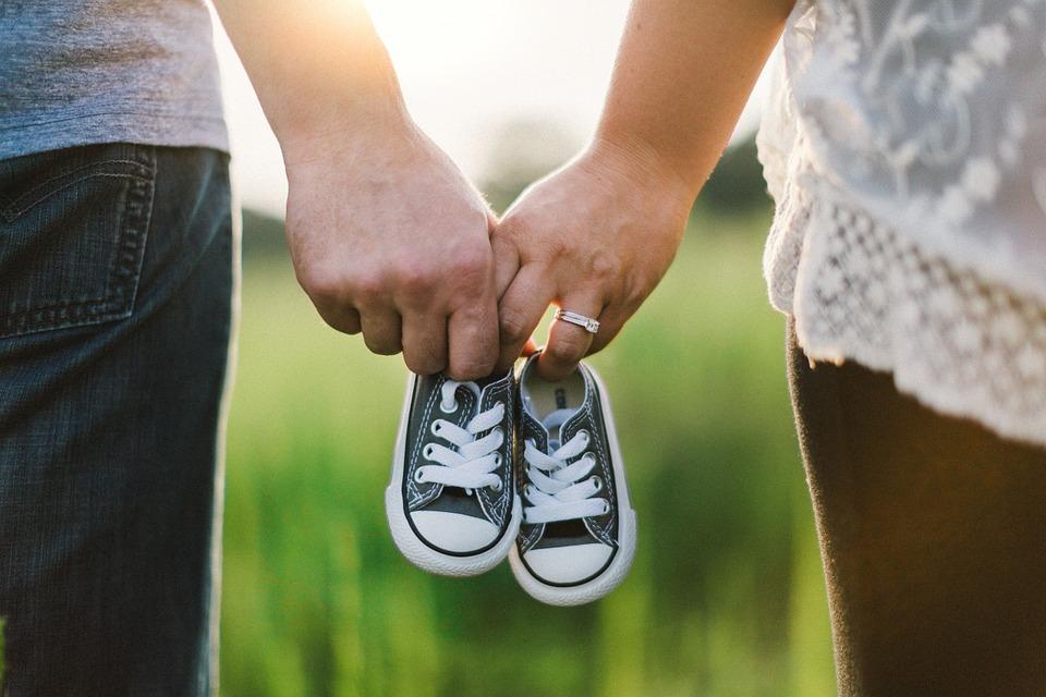 Die Hände zweier Menschen halten gemeinsam kleine Schuhe