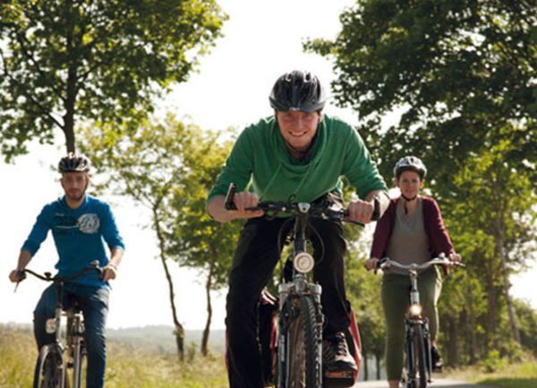 Drei Radfahrer sind auf einer ländlichen Straße unterwegs