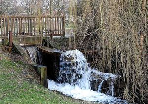 Kleine Holzbrücke und Wassermühle am Tag