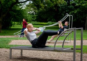 Drei Menschen nutzen Fitnessgeräte im Freien