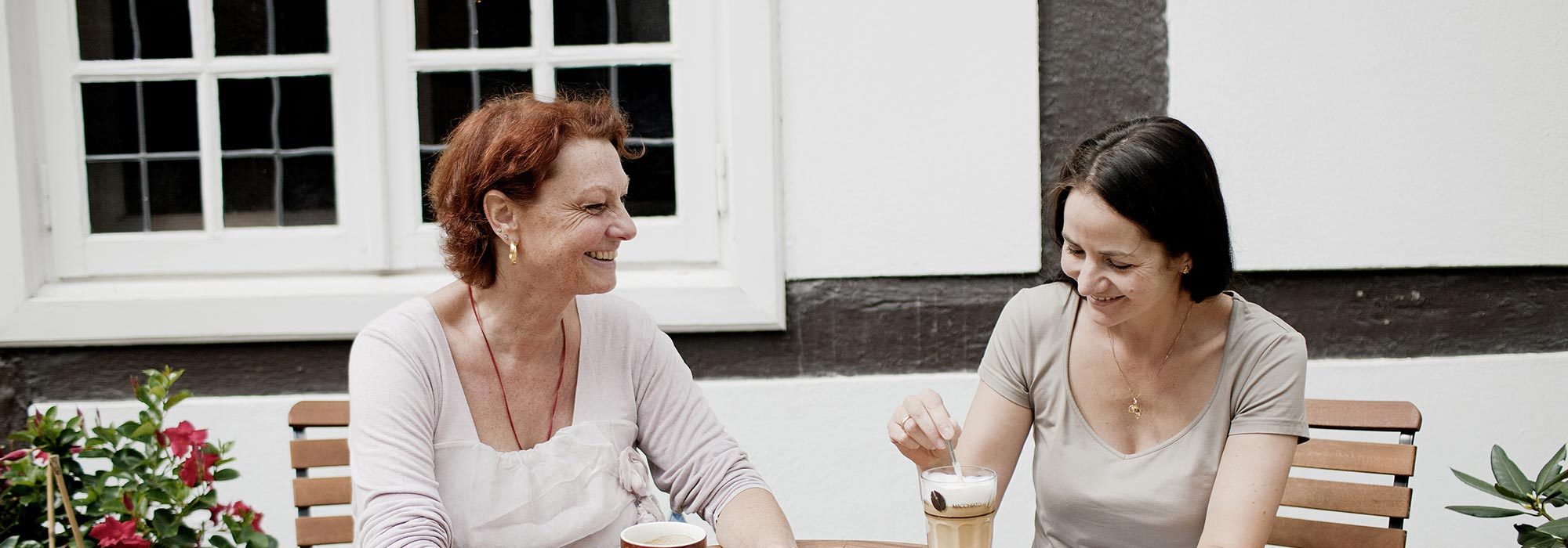 Zwei Frauen sitzen draußen und trinken einen Kaffee