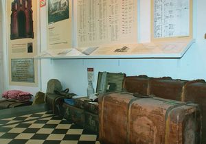 Koffer und andere historische Gegenstände unter Informationstafeln