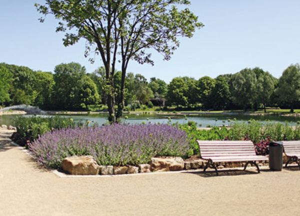 Kurpark mit Bänken, Grünflächen und Gewässer bei blauem Himmel