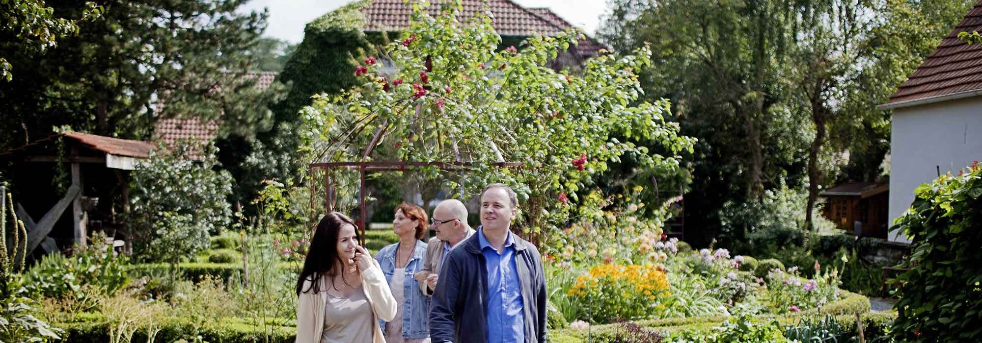 Zwei Männer und zwei Frauen spazieren durch einen Garten